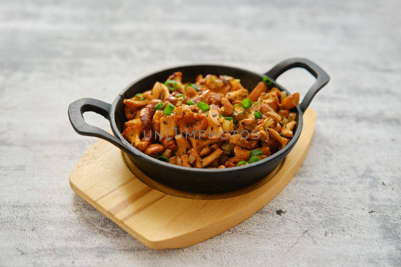 Wild chanterelle mushrooms roasted with thyme and spring onion in a frying pan