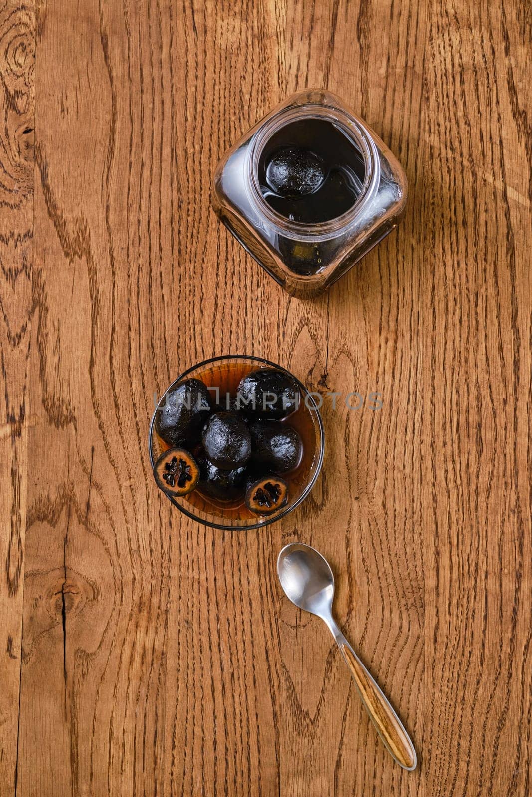 Overhead view of wooden table with saucer and jar with homemade preserved walnut jam