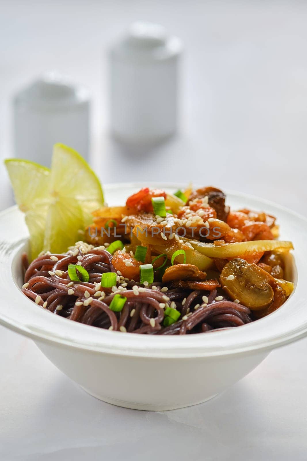 Close-up view of black rice noodles with shrimps and mushrooms in a plate