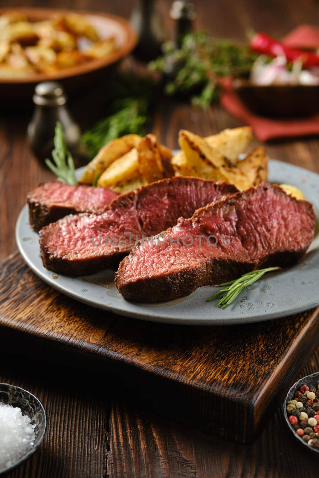 Rustic dinner with juicy top blade beef steak on a plate surrounded with spice and herbs