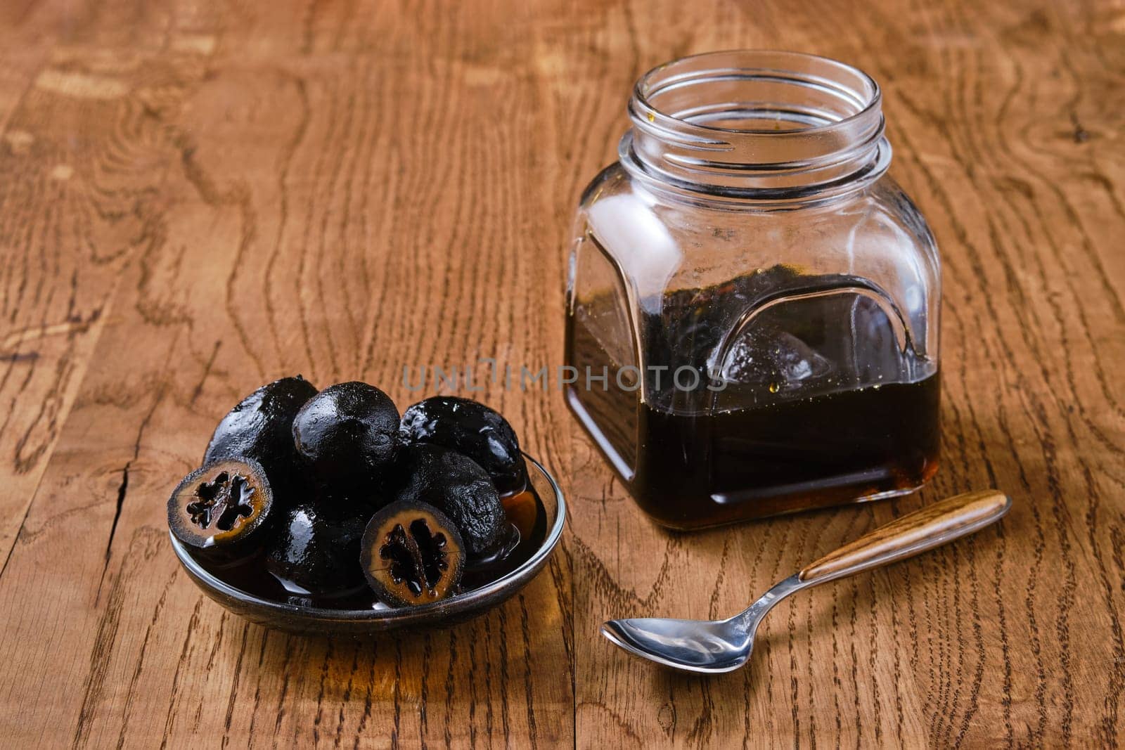 Saucer and jar with homemade preserved walnuts on wooden background