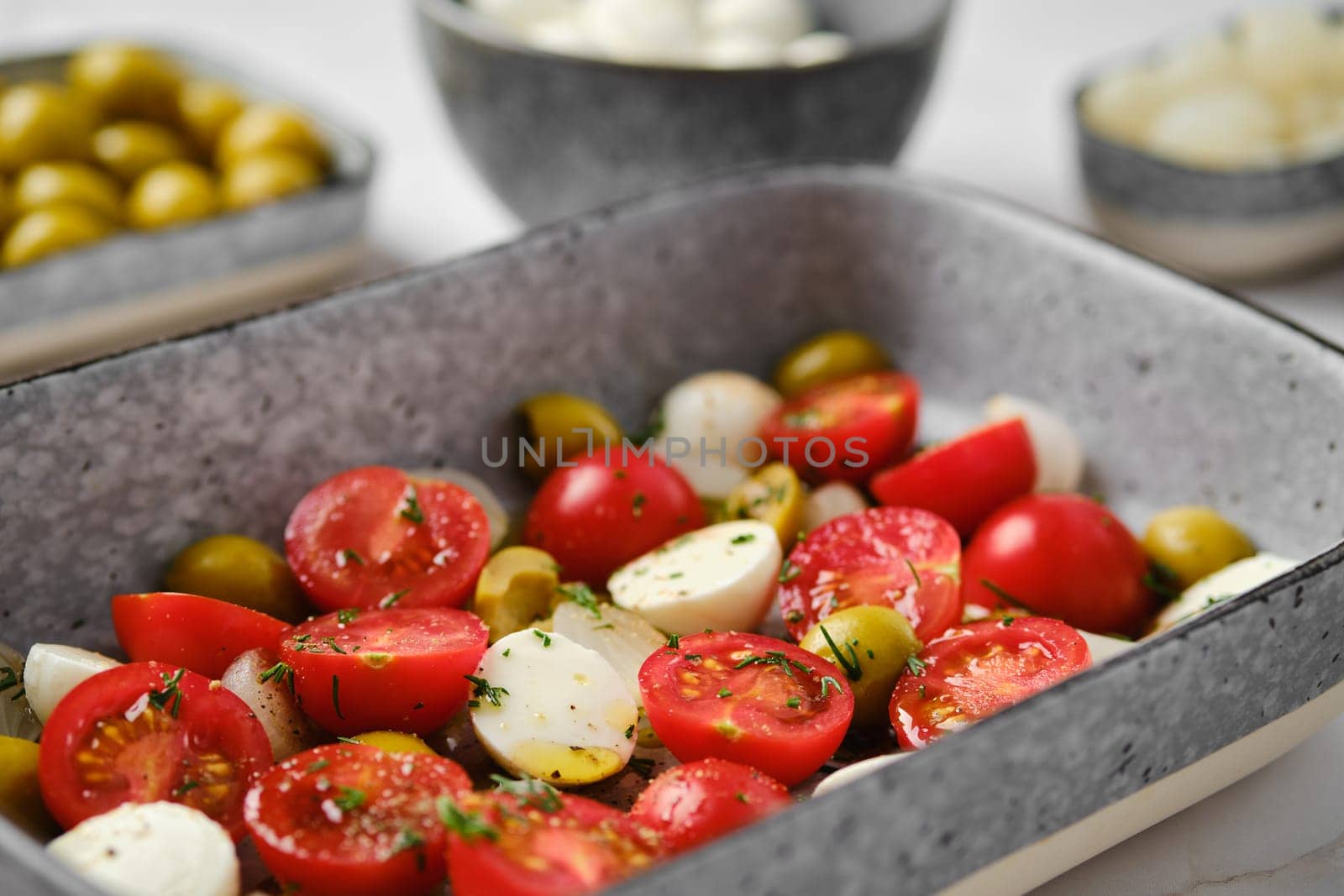 Close-up view of caprese salad with cherry tomatoes, olives, pickled onion and mozzarella