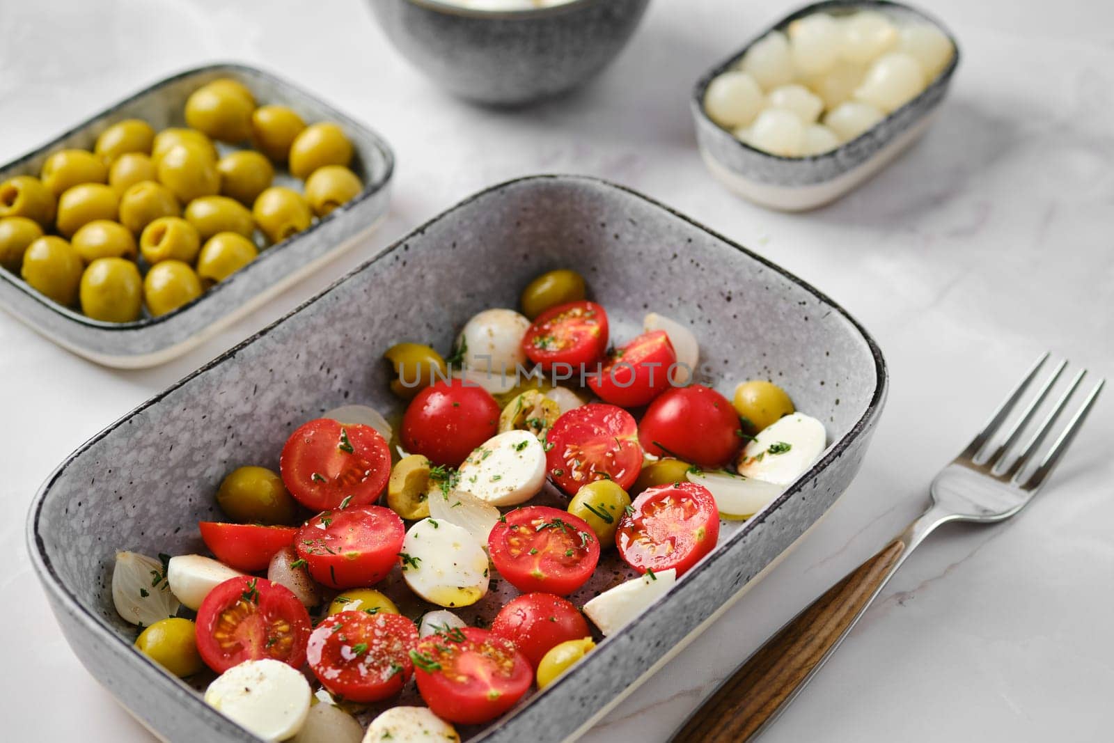 Close-up view of mozzarella, tomato and olives salad seasoned with olive oil and balsamic vinegar