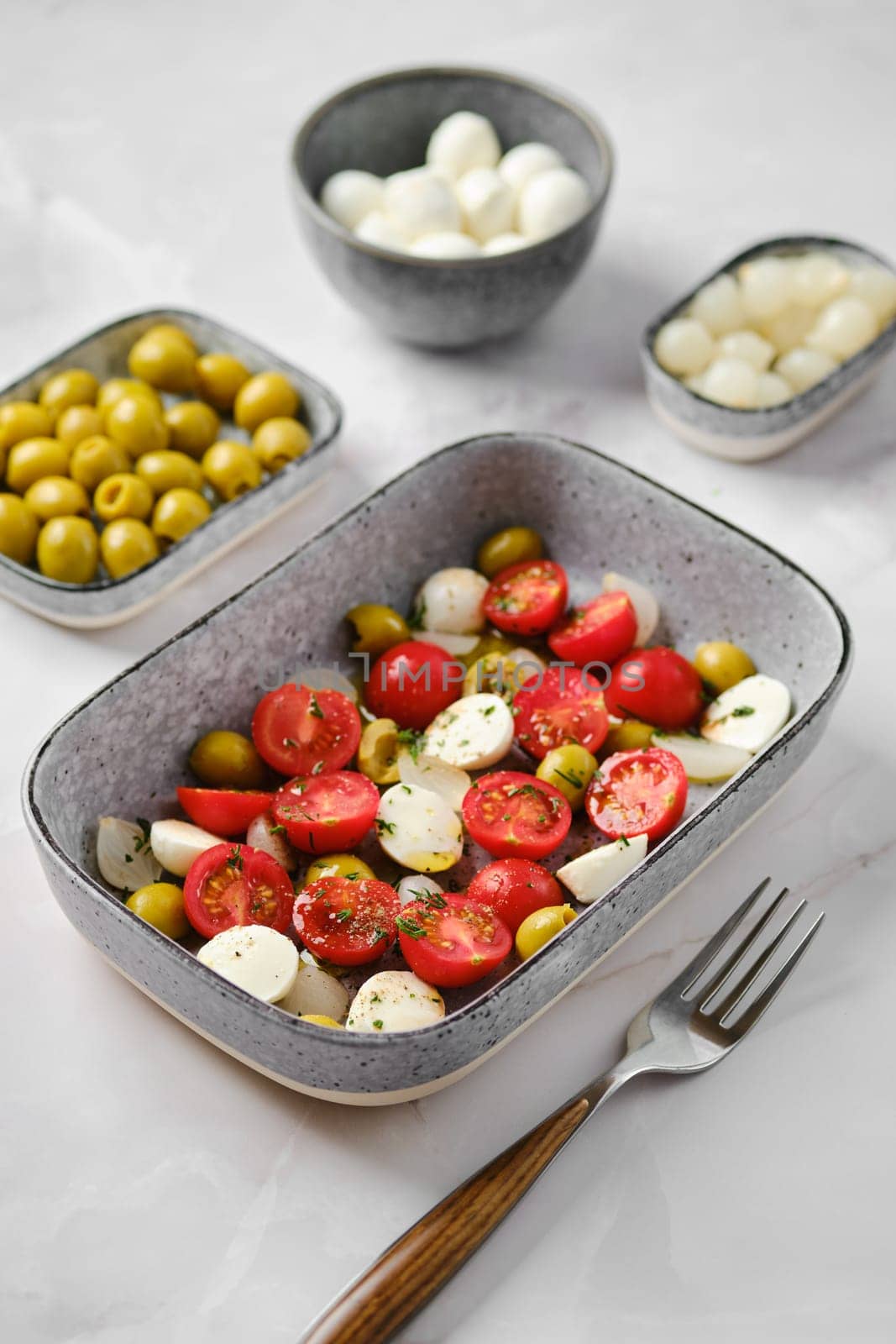 Mozzarella, tomato and olives salad seasoned with olive oil and balsamic vinegar