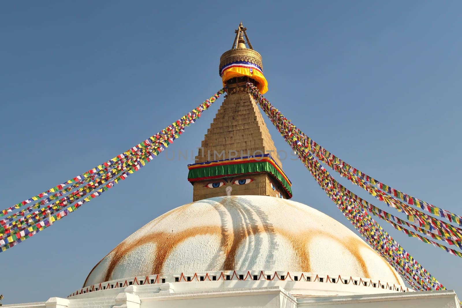 The upper part of the Boudhanath Stupa, many colorful prayer flags are attached to it, Kathmandu, Nepal 2022