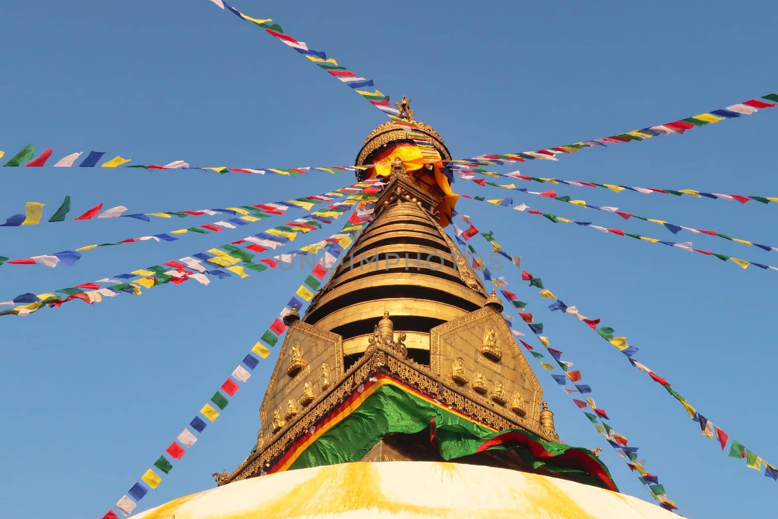 The golden top of the Swayambhunath Stupa, Temple, decorated with many colorful prayer flags, Kathmandu, Nepal 2022