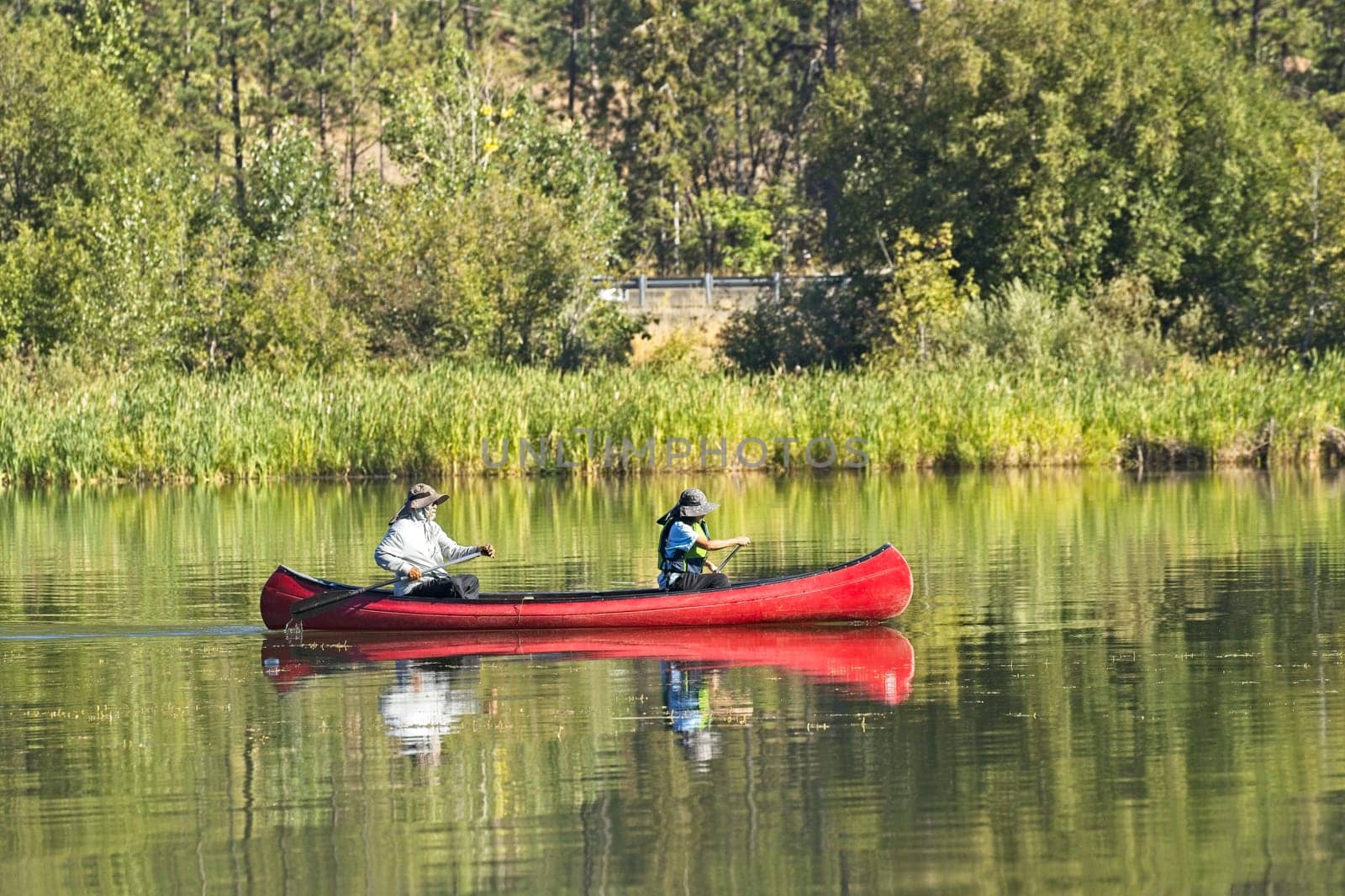 An editorial photo of a mature couple paddling the canoe on Coeur d'Alene Lake in north Idaho.