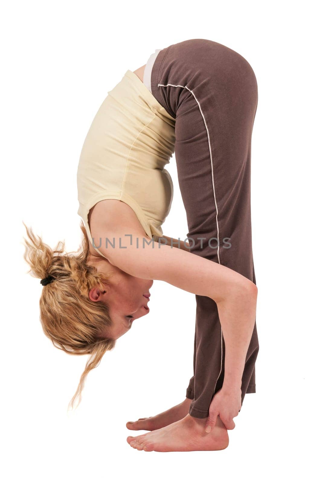 Profile full body view of young woman in sport dress doing yoga exercise Standing Forward Bend Pada Hastasana with arms outstretched at ankles isolated on white.