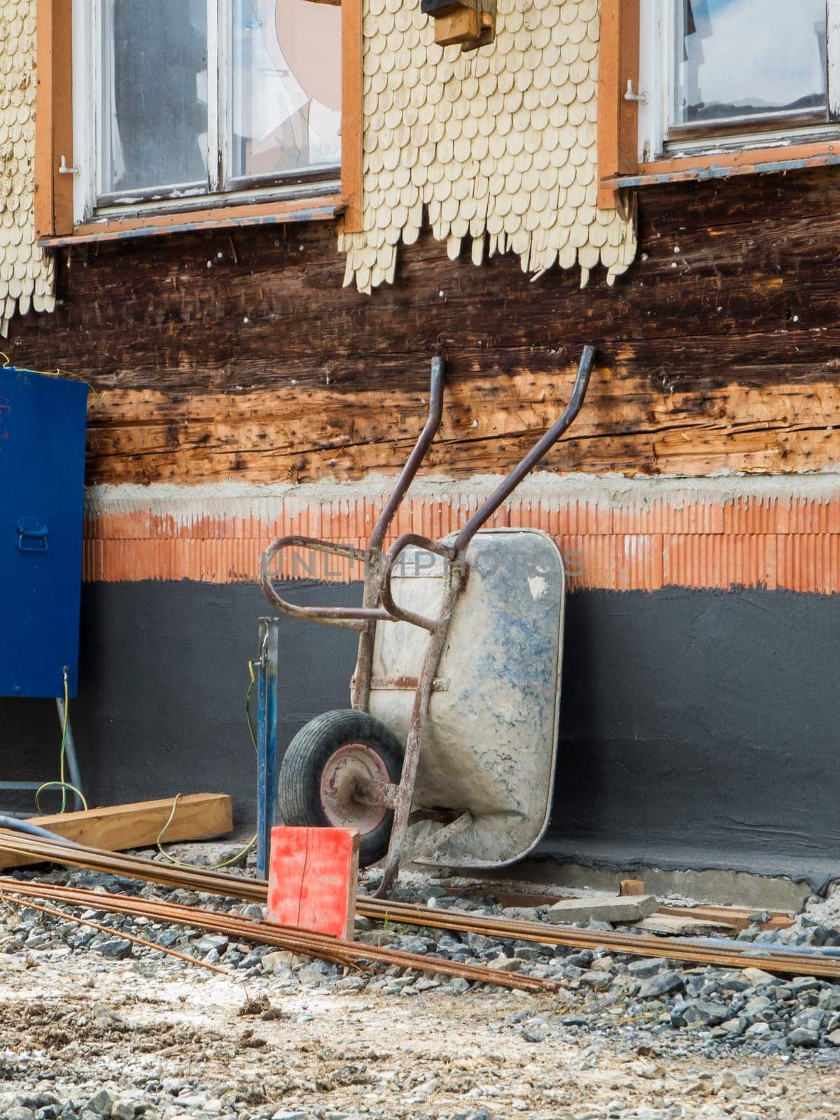 Reconstructing construction site of a wooden house in Bavaria with a wheelbarrow placed against the wall.