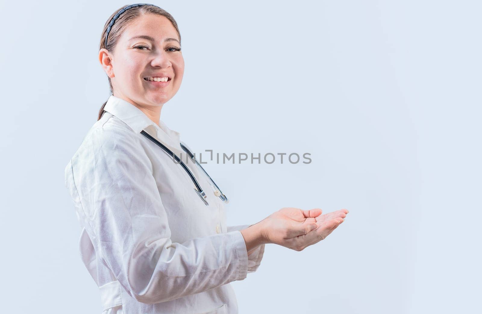 Beautiful smiling female doctor showing an advertisement with palms. Happy female doctor presenting something with palms