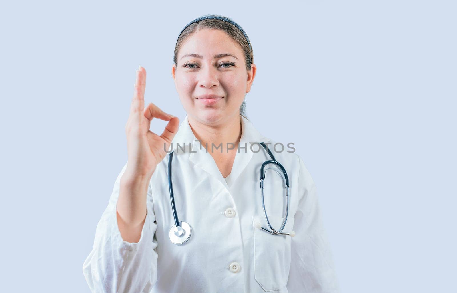 Beautiful female doctor gesturing approval isolated. Smiling female doctor approving and recommending isolated