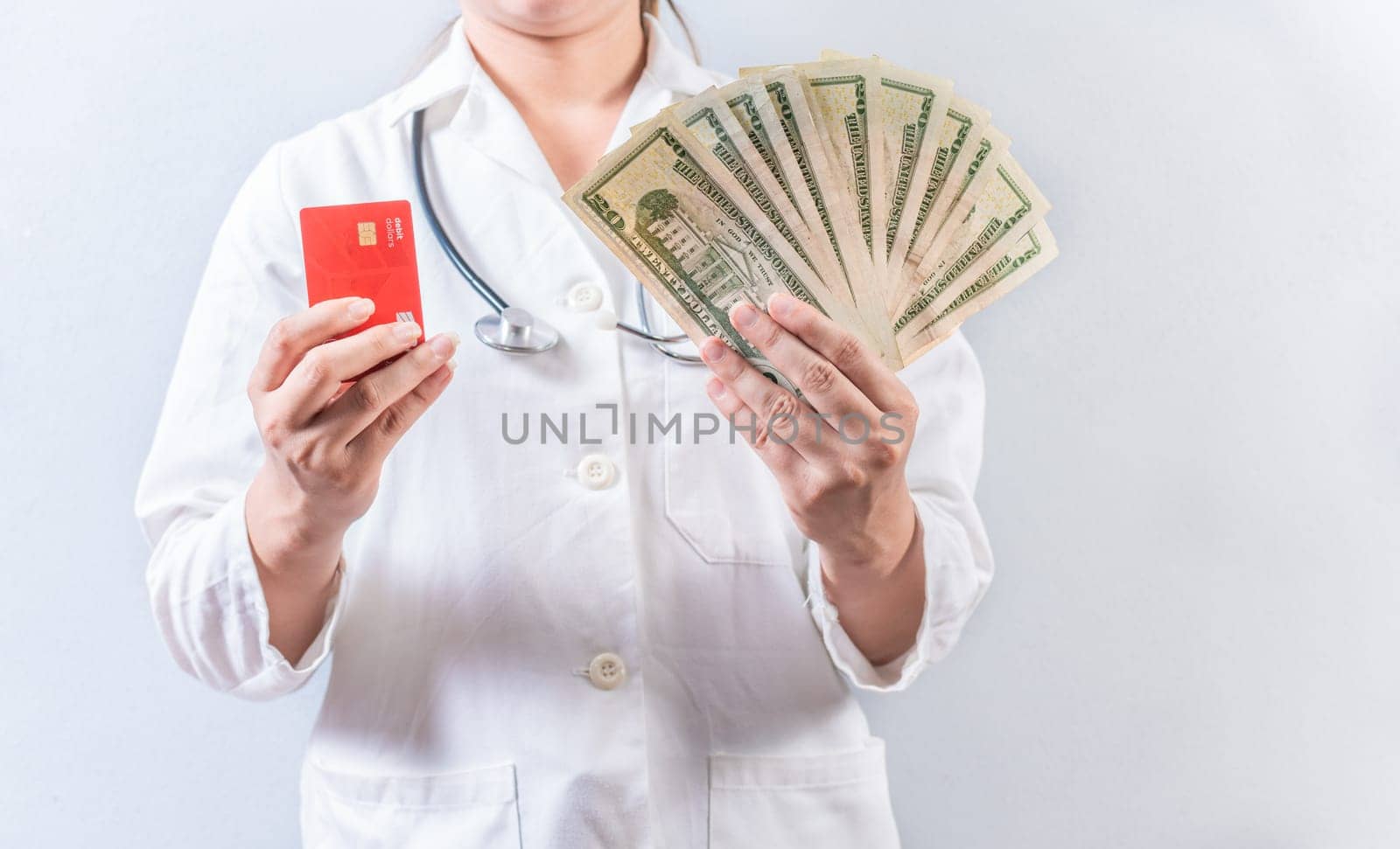 Female doctor hands holding credit card and money isolated. Unrecognizable doctor holding money and credit cards isolated