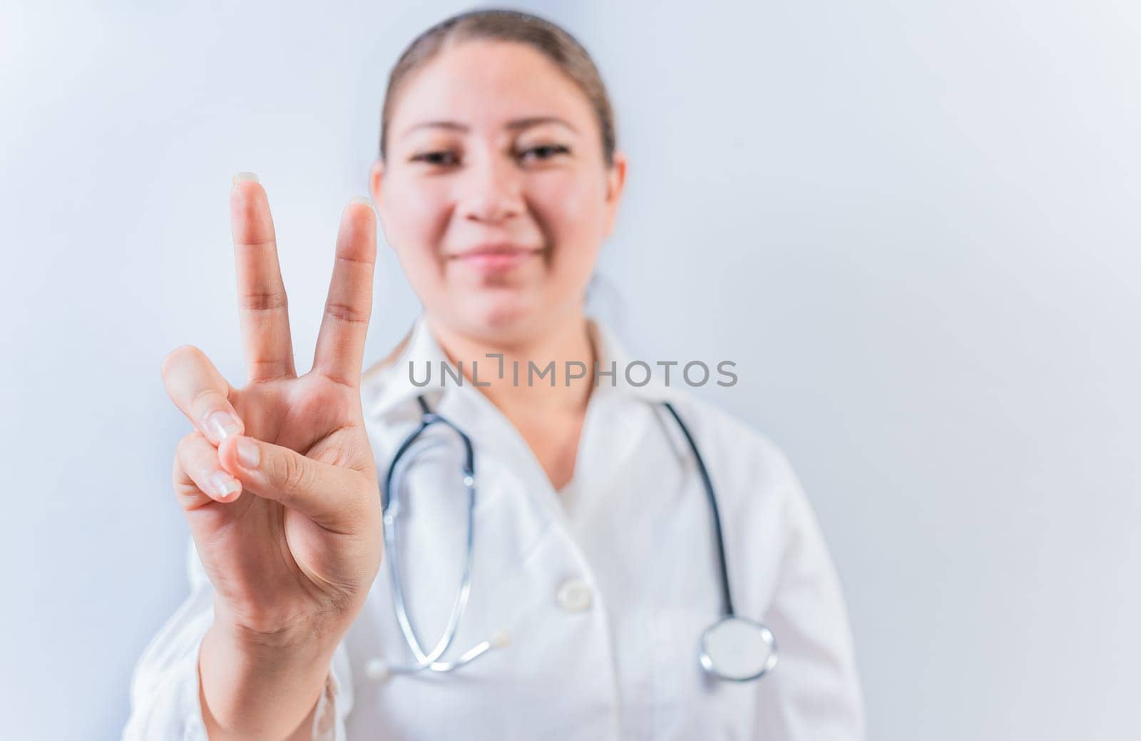 Female doctor counting number TWO isolated. Young female doctor counting number 2 on isolated background