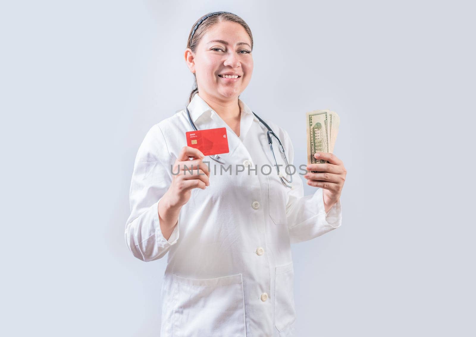 Beautiful and smiling female doctor holding money and credit cards. Happy female doctor holding credit card and money isolated