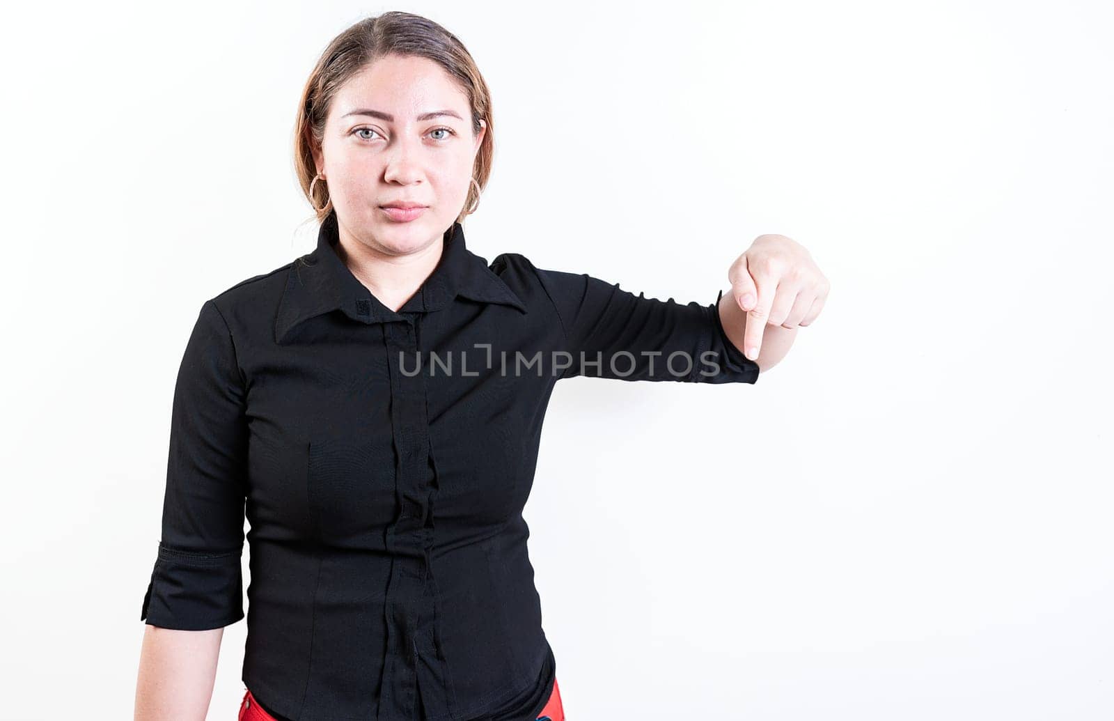 Young woman pointing advertising down. Beautiful latin girl pointing down an advertisement. Latin people pointing down at a banner