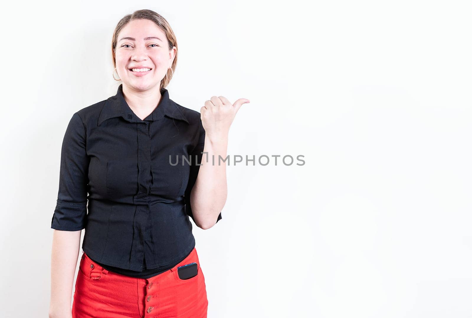 Beautiful young girl pointing to a banner to the side. Happy latin woman pointing a promo isolated. Cheerful latin girl pointing an offer isolated