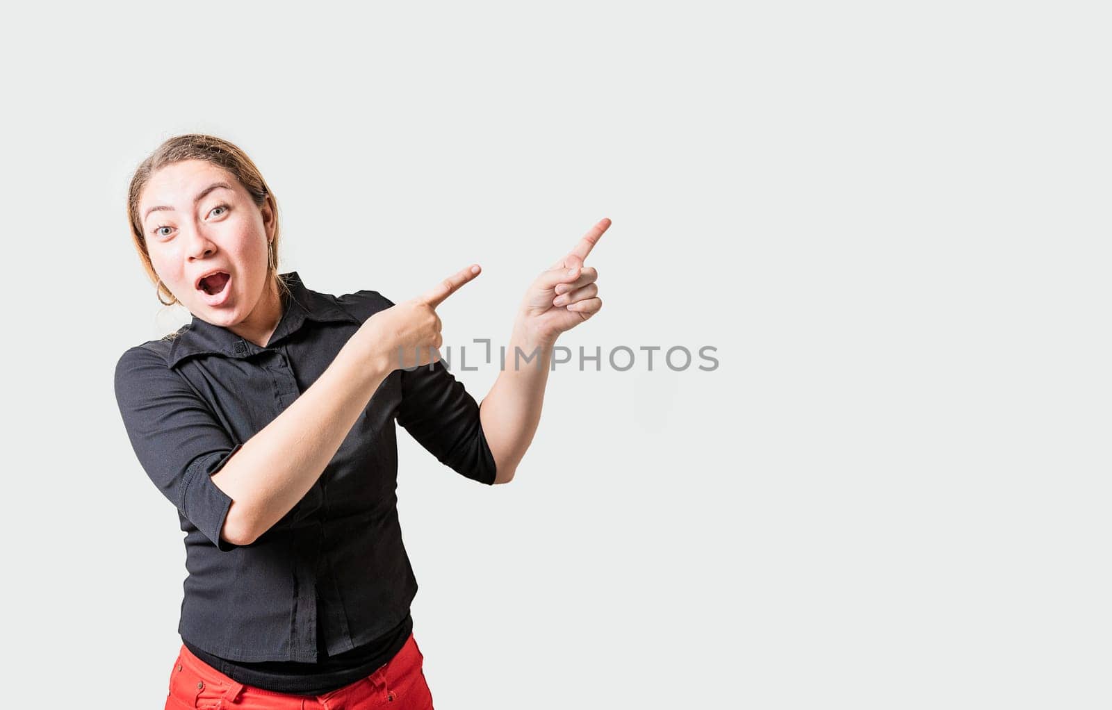 Amazed girl pointing an advertising side. Astonished girl pointing to a banner to the side. people pointing a promo