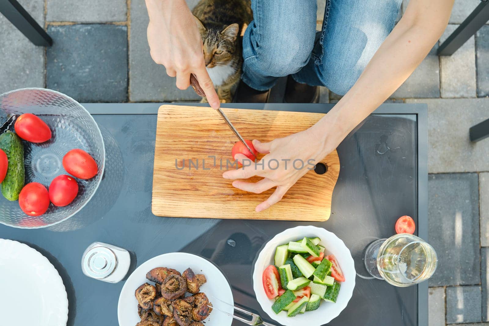 Overhead view of unrecognizable woman preparing salad outdoors while sitting in backyard