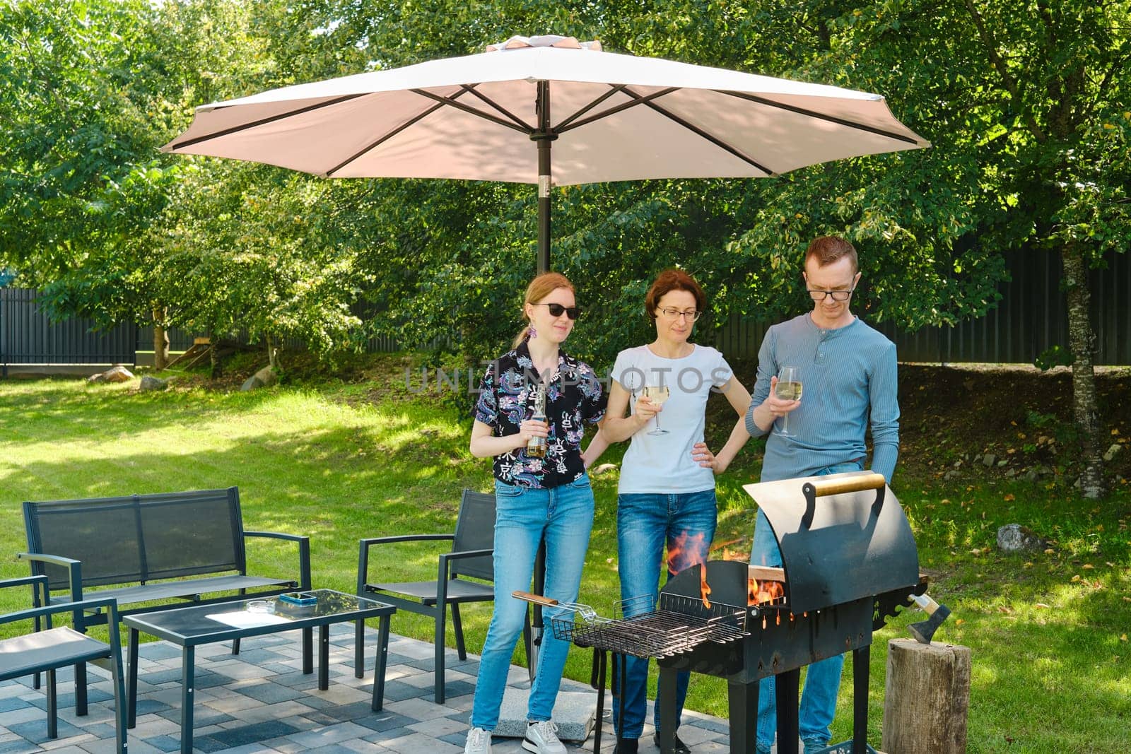 Family gathered next to a barbecue grill on the lawn