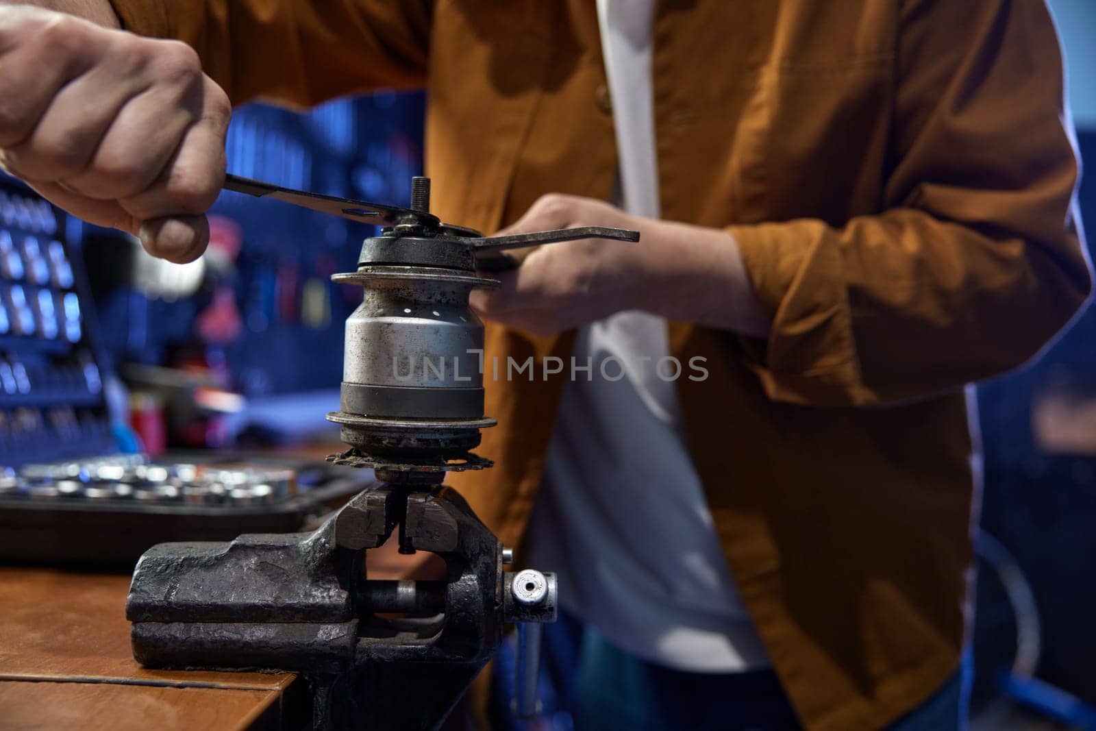 Professional bike mechanic disassembling and servicing bicycle internal-geared hub on manual vice in repair shop