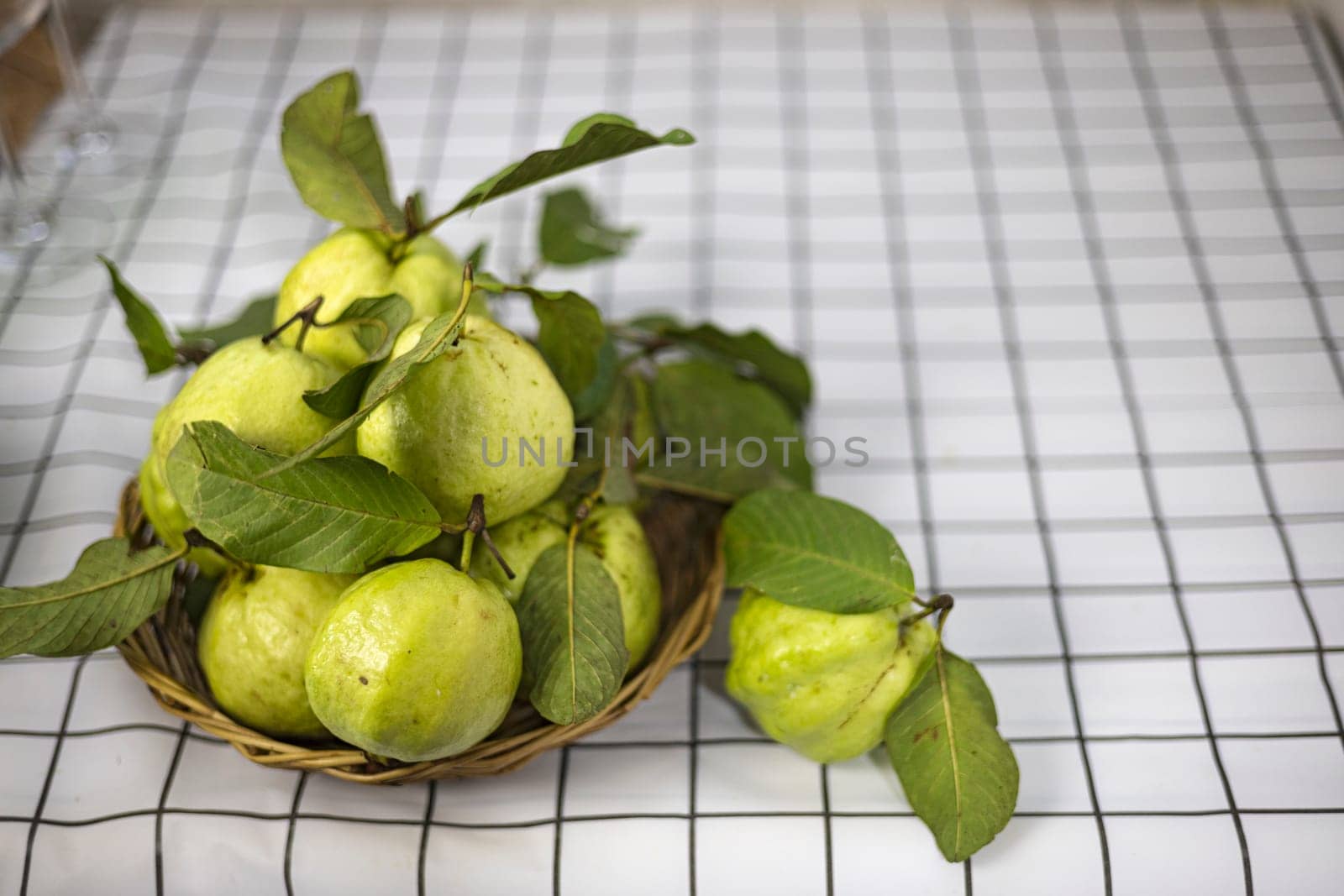 Green guava in the bamboo basket on the table.