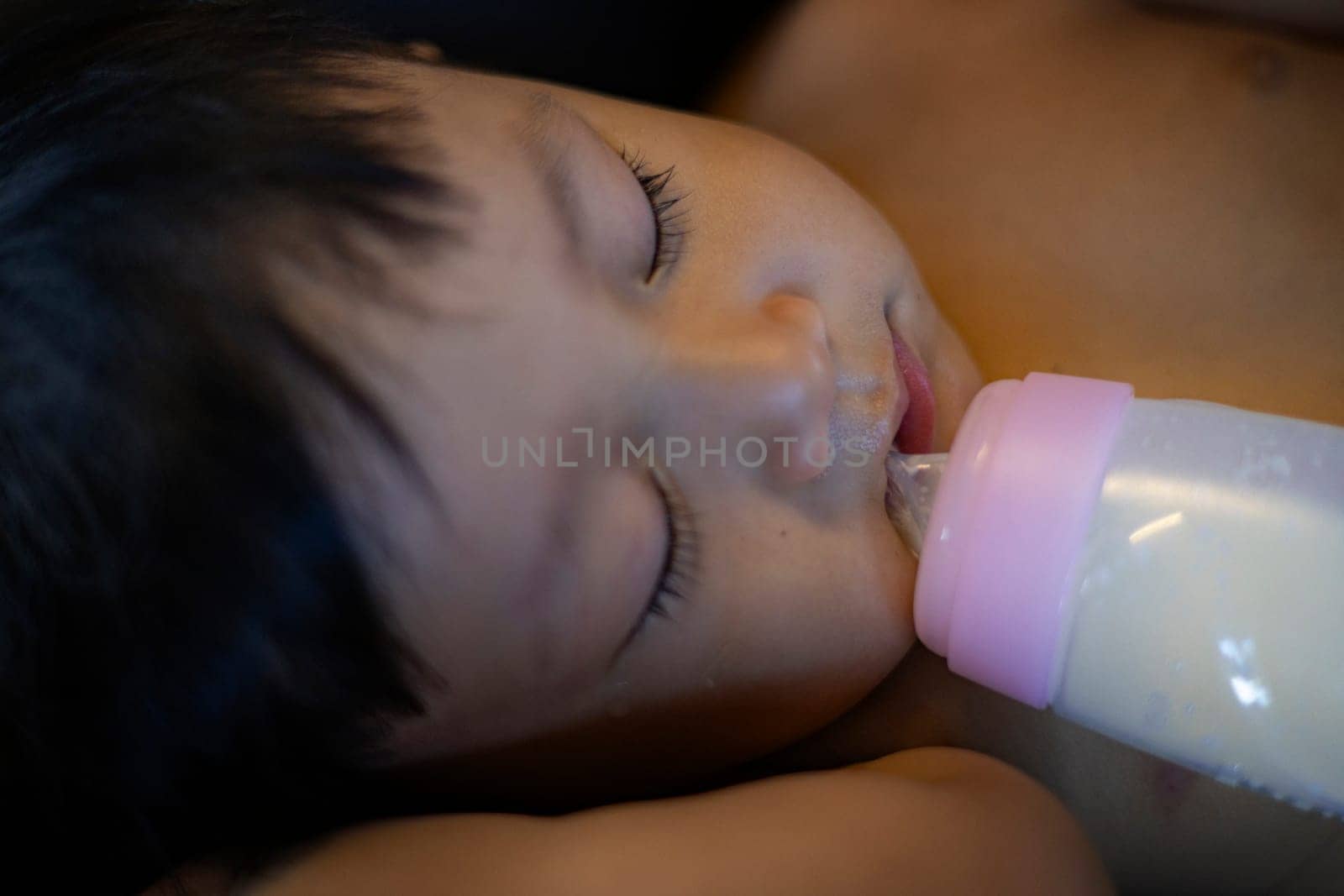 Sleeping baby with a milk bottle.