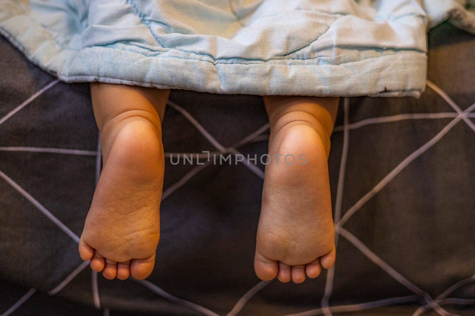 Legs of child sticking out from under the blankets.