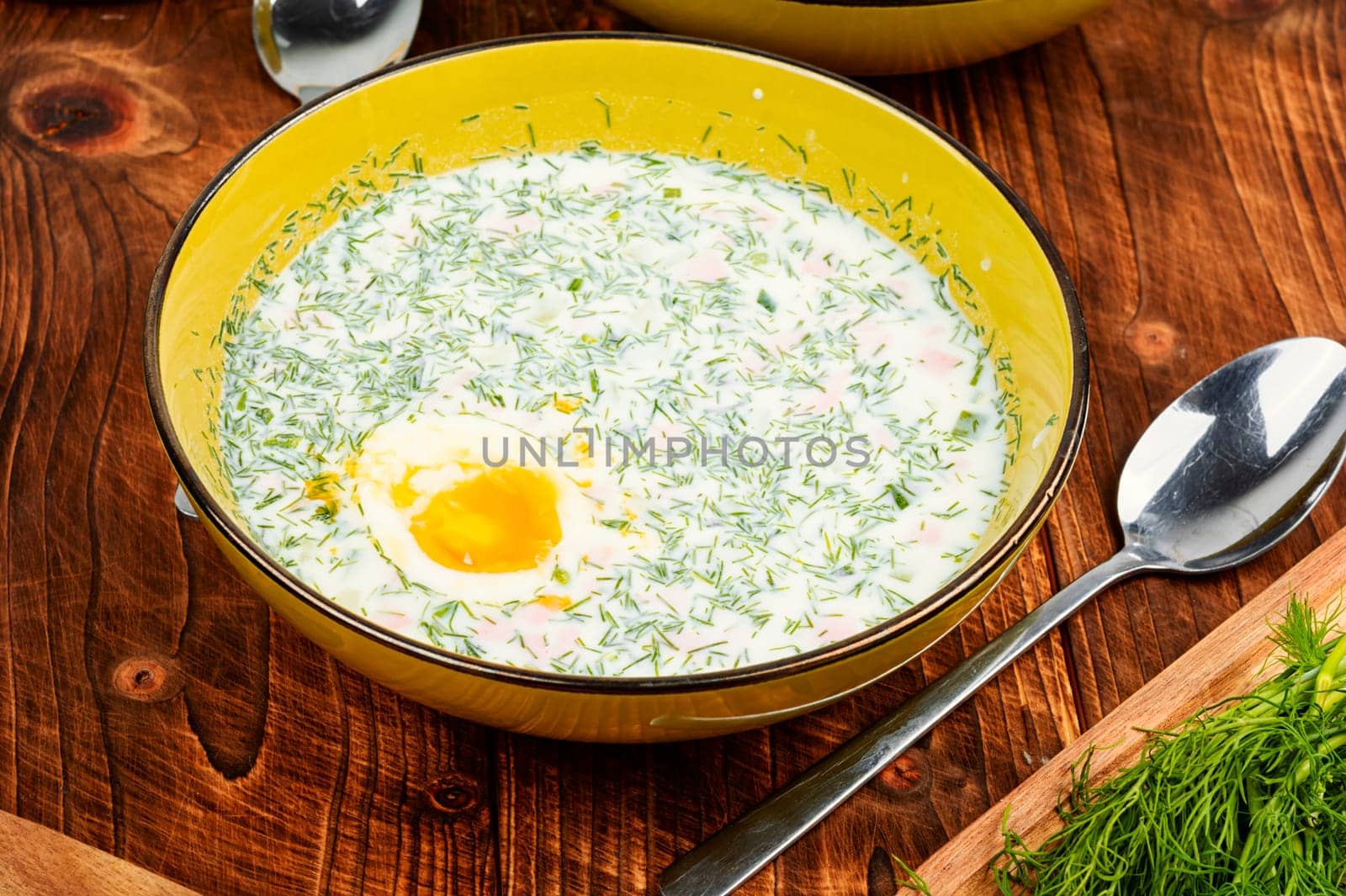 Delicious cold summer soup okroshka with boiled sausage in bowl