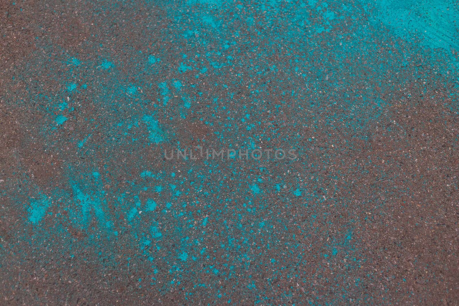 Multicolored dry blue paints on gray asphalt. Powder coating at the Holi festival. Place for inscription