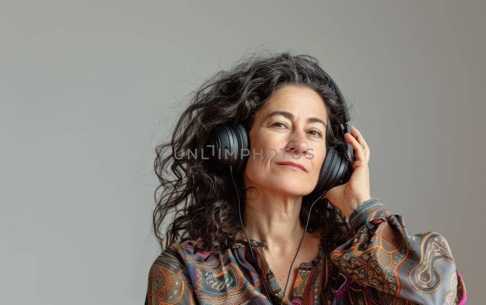 A contemplative woman listens to music, her headphones encasing her in a world of sound. Her thoughtful gaze suggests deep engagement with the melody