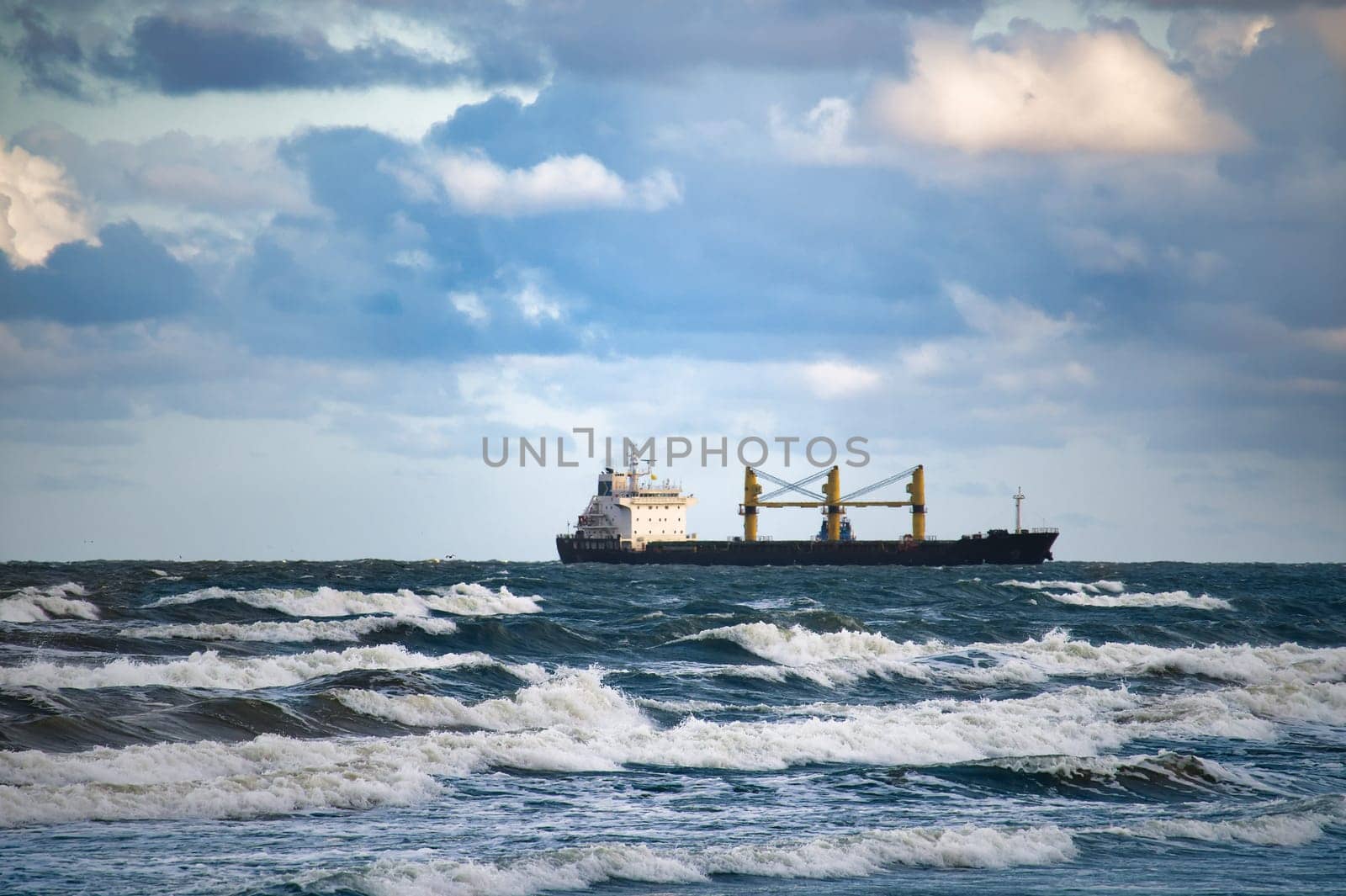 Cargo ship sailing through turbulent ocean waves against a backdrop of clouds, capturing maritime transport and adventure.