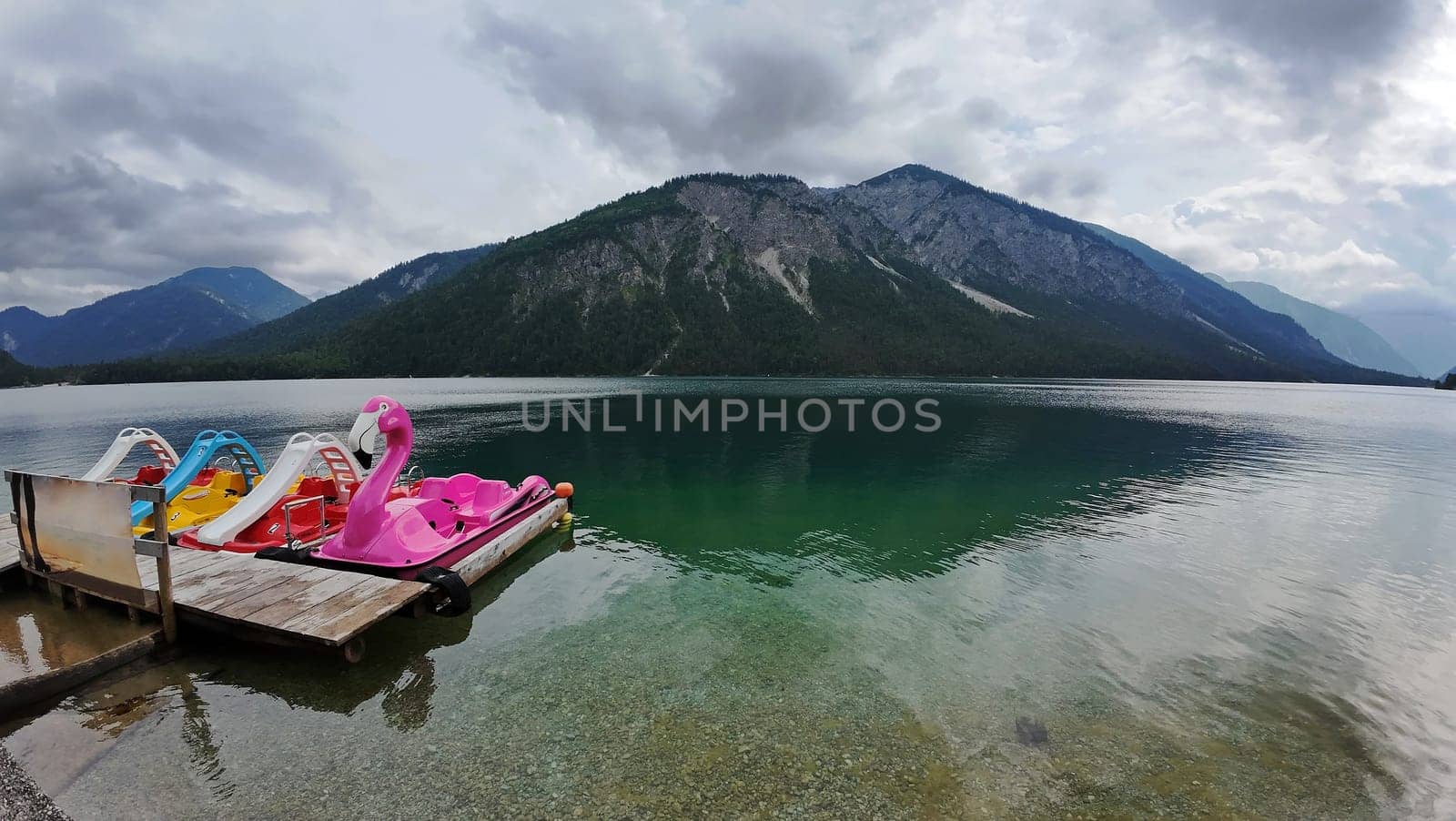 Colorful pedal boats on the Plansee in Austria with a dark cloudy atmosphere