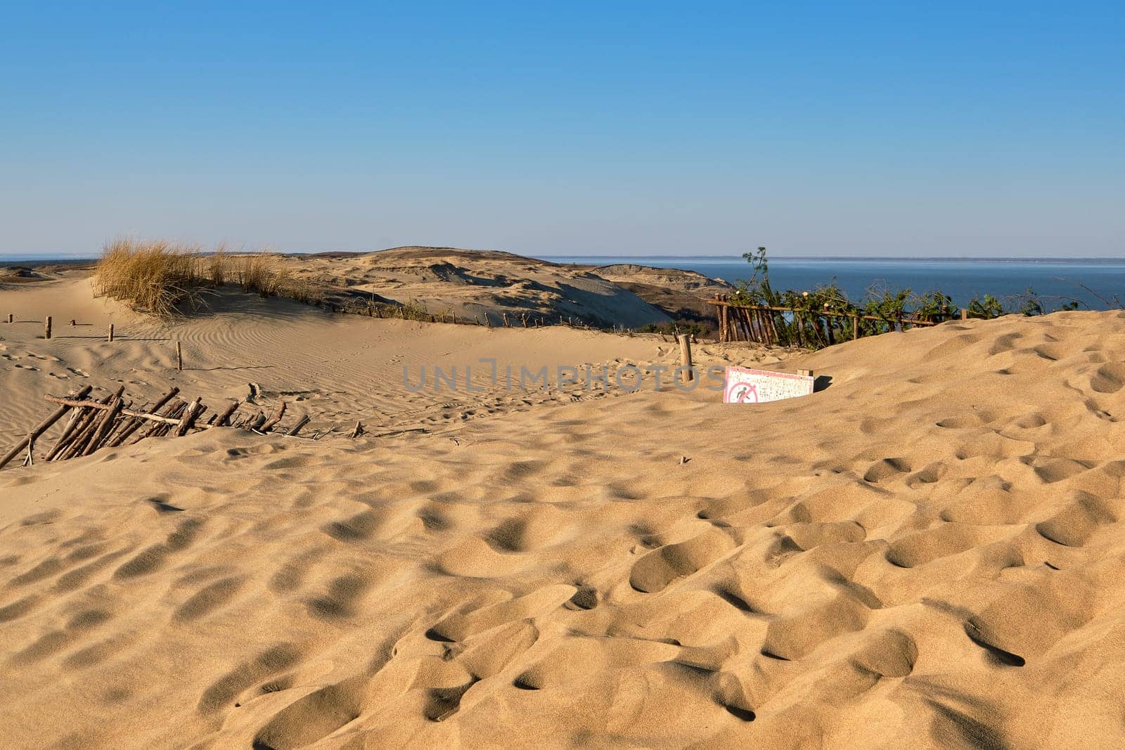 View of nordic dunes, footprints and bushes of Curonian spit, Nida, Klaipeda, Lithuania at sunset on early spring. Signs deep in sands