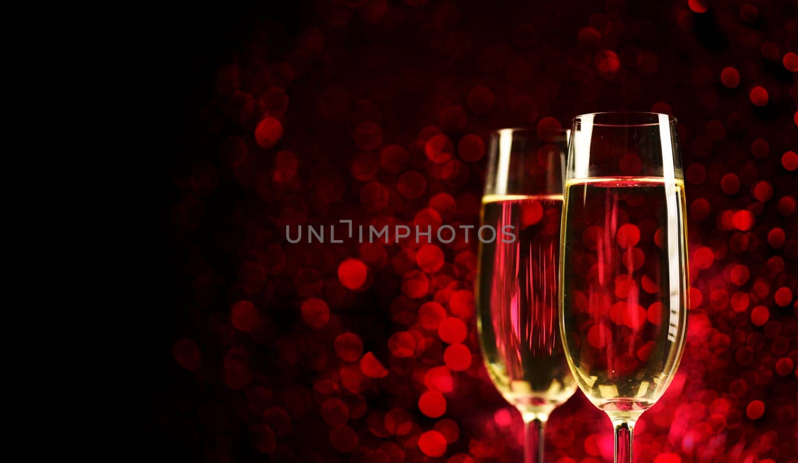 Two champagne glasses on sparkling red bokeh background. Celebration toast flutes. Valentine's day dinner invitation. Christmas and new year holiday party.
