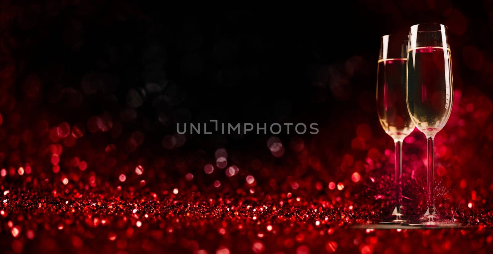 Two champagne glasses on sparkling red bokeh background. Celebration toast flutes. Valentine's day dinner invitation. Christmas and new year holiday party.