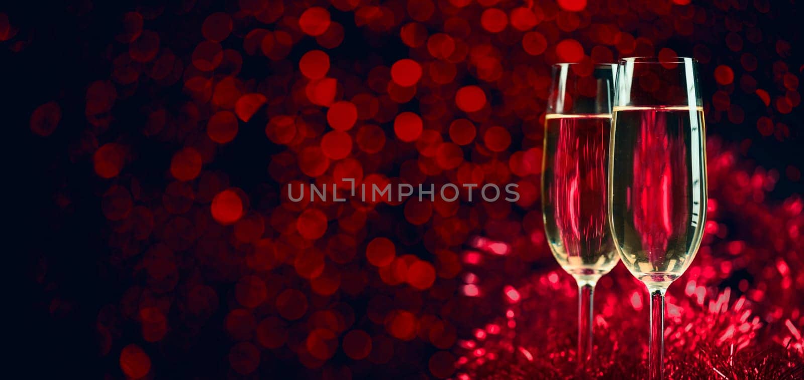 Two champagne glasses on sparkling red bokeh background. Celebration toast flutes. Valentine's day dinner invitation. Christmas and new year holiday party.