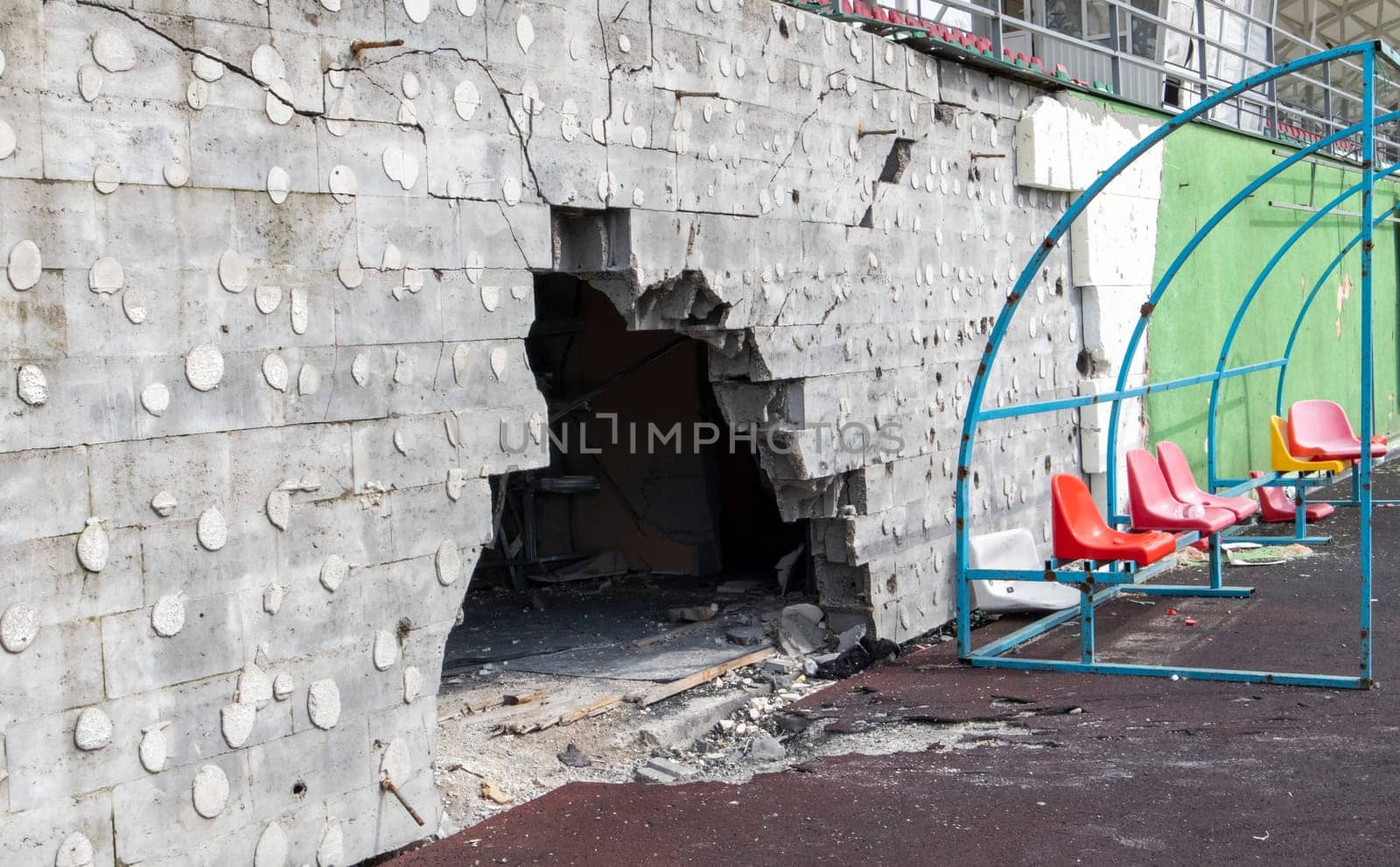 War in Ukraine. Broken plastic benches for fans on the podium, in a destroyed football stadium in a children's football school. The consequences of shelling from artillery