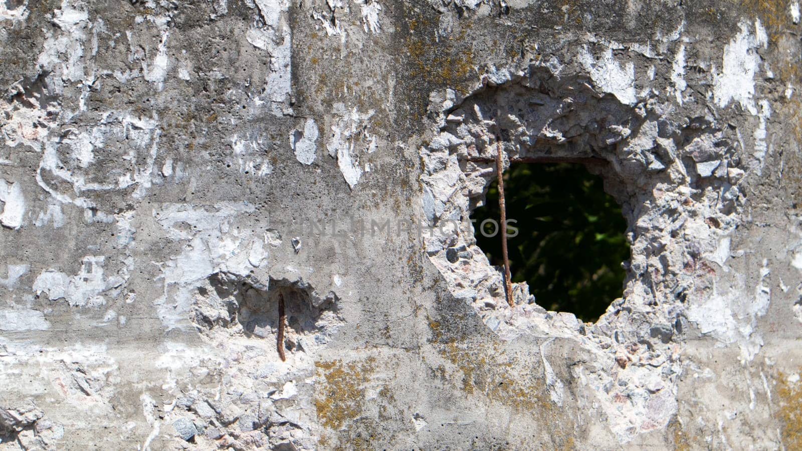 Photo of a broken cement wall or fence. Stone grunge odd wall with a hole. Damaged grungy crack and broken concrete wall