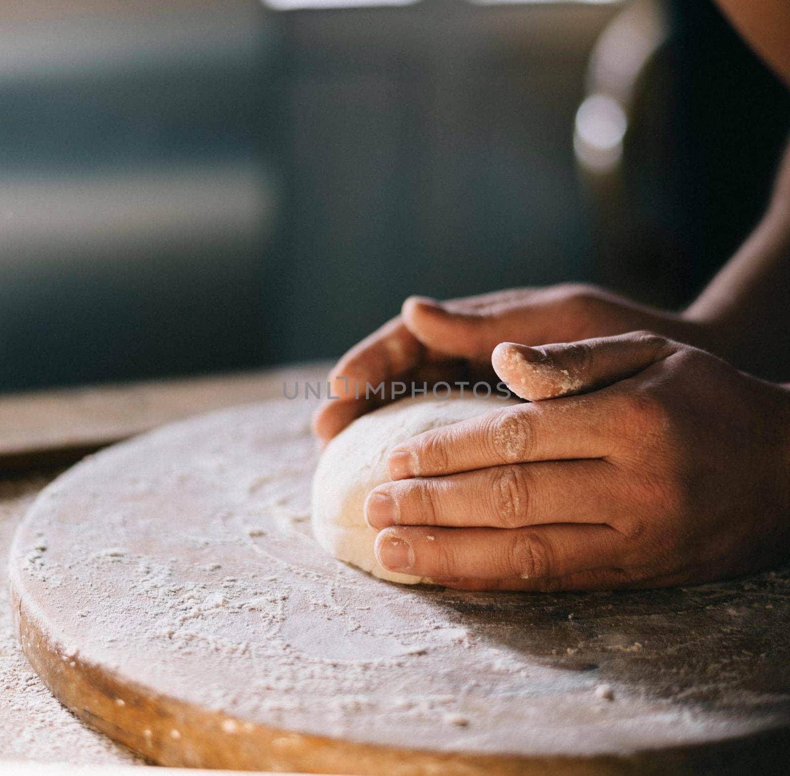 Man kneading and baking homemade pizza dough in the kitchen. Closeup on baker's hands preparing loaf of bread. Cooking and food preparation at home.