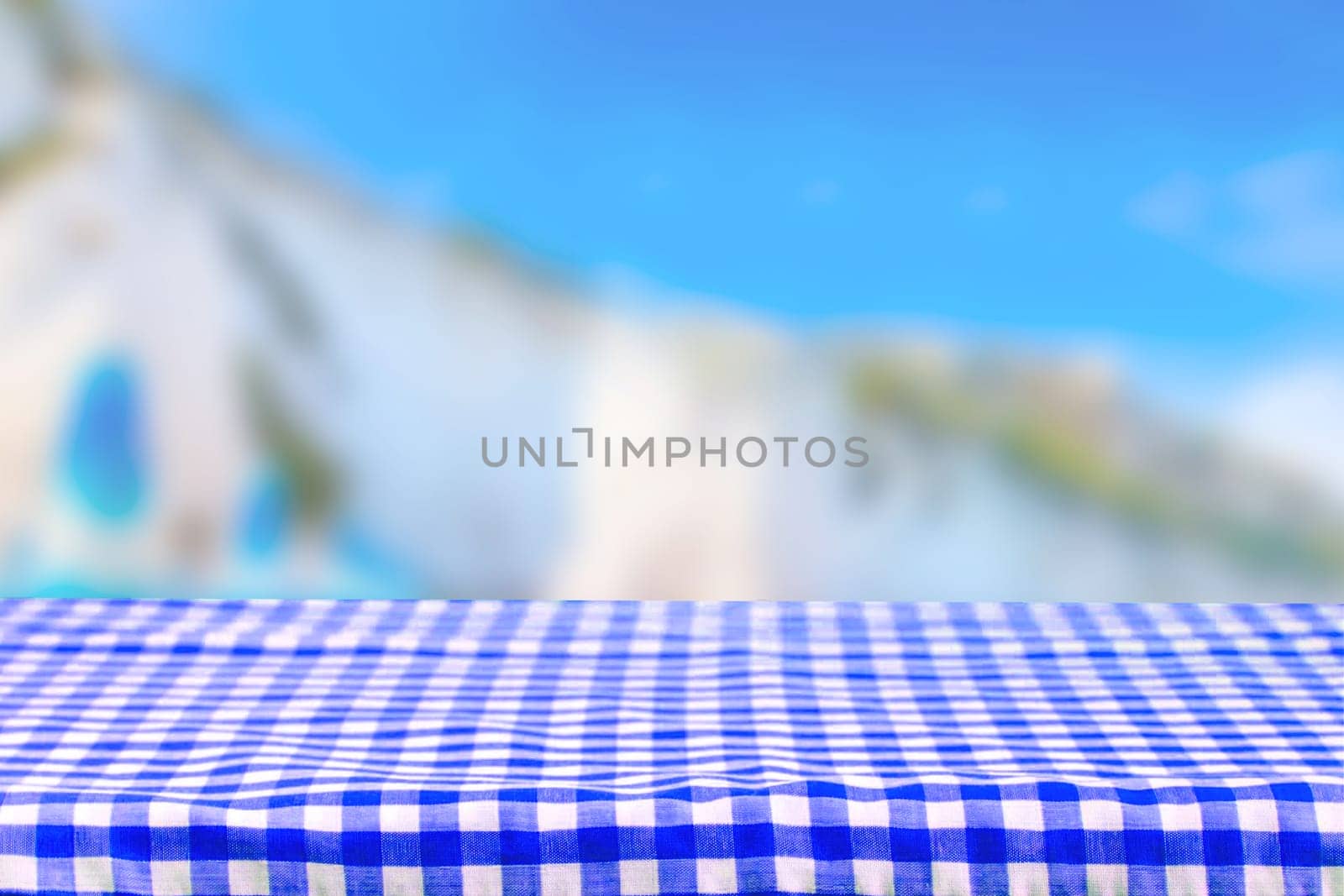 Empty table product. Empty colorful checkered tablecloth over abstract blurred natural bright background texture with space for food and product display montage.