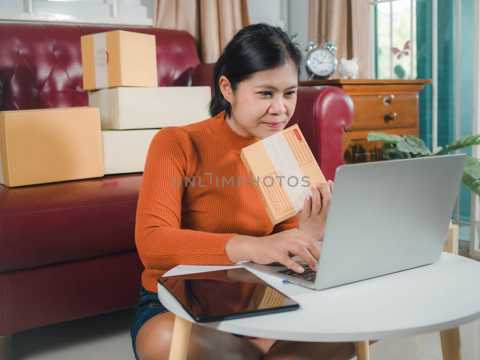 Asia women working business SME online at home her checking order from laptop for customer and online delivery for ready packing, Checking orders from customers with digital laptop, Small business.