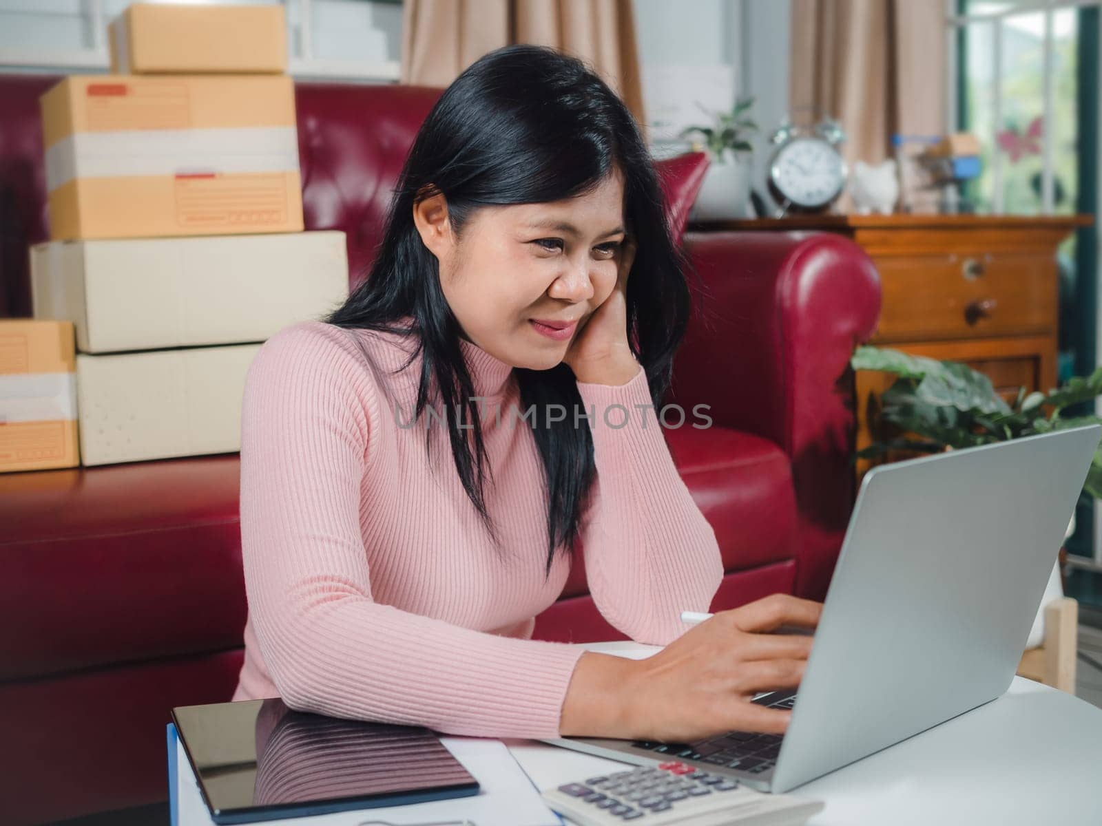 Businesswomen working business SME online at home her checking order from laptop for customer and online delivery for ready packing, Checking orders from customers with digital laptop, Small business.