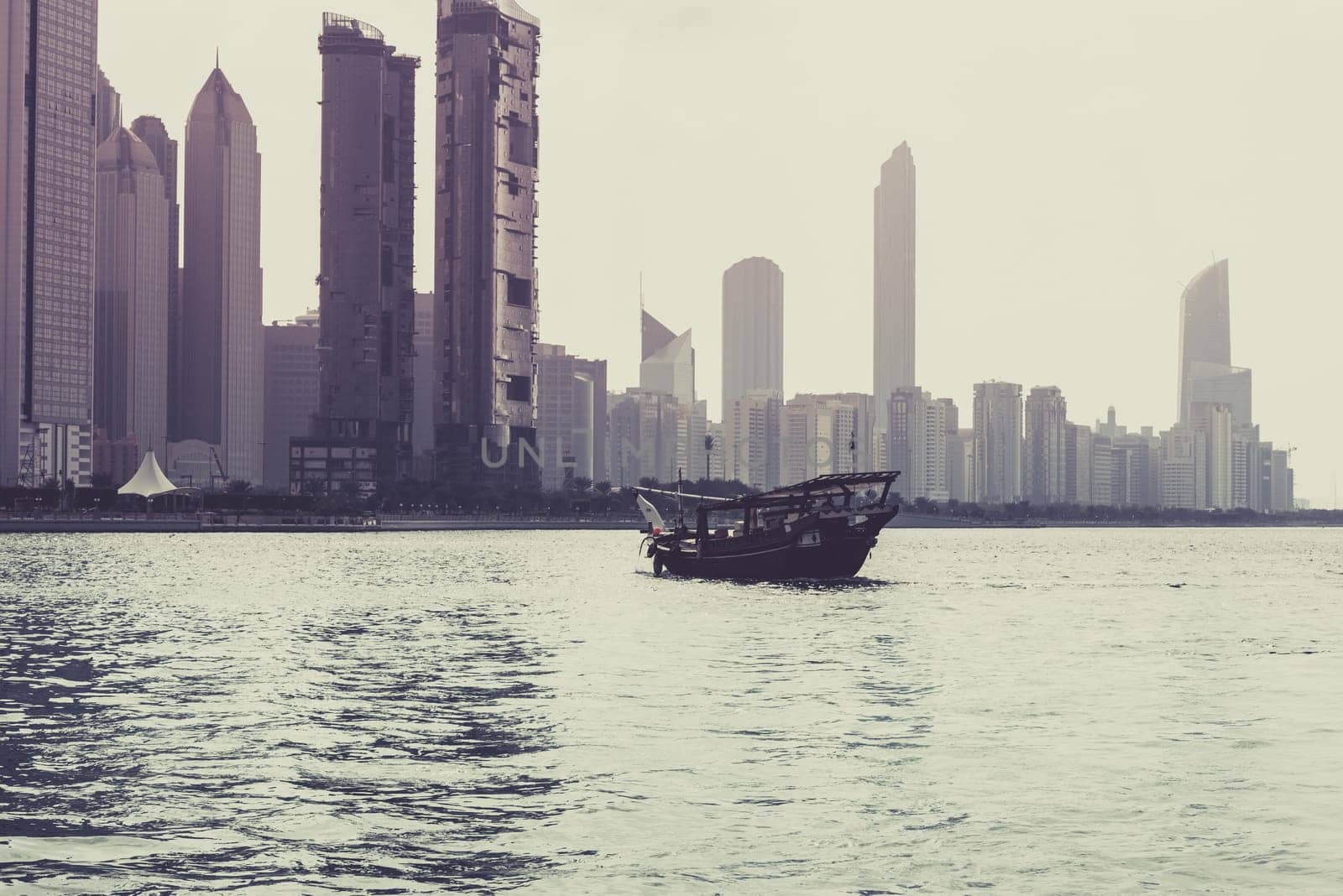 Abu Dhabi buildings skyline with old fishing boat on the front