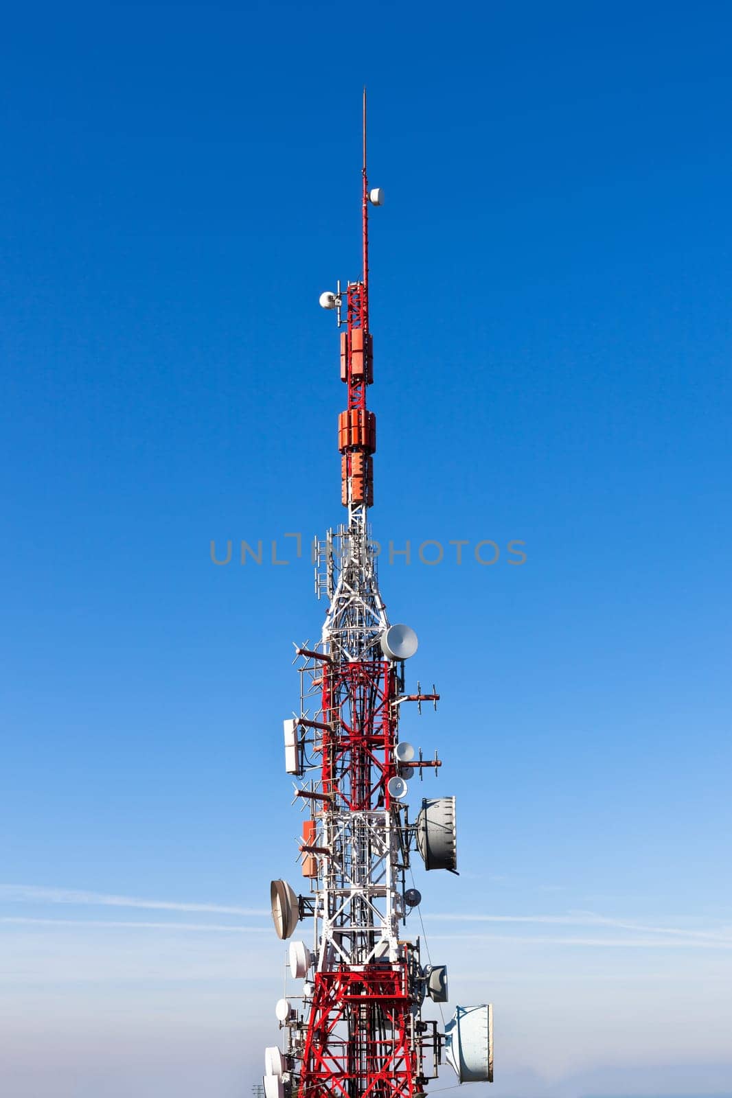 A radio communications tower with dishes against a deep blue sky