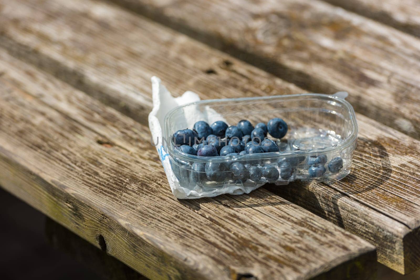 Blueberries in a plastic box on the wooden rustic table. Small GRIP