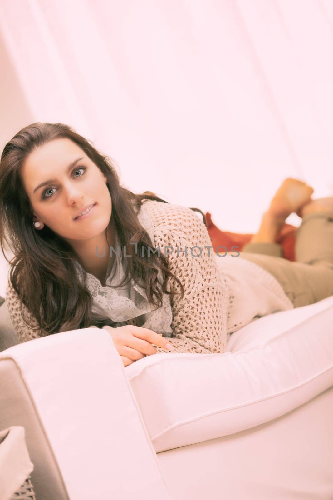 Living room, A young woman is lying on her stomach on her couch, enjoying a relaxing moment at home