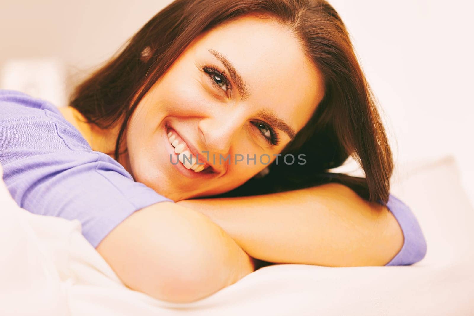 Living room, An attractive young woman is lying on her bed smiling with her head resting on her folded arms