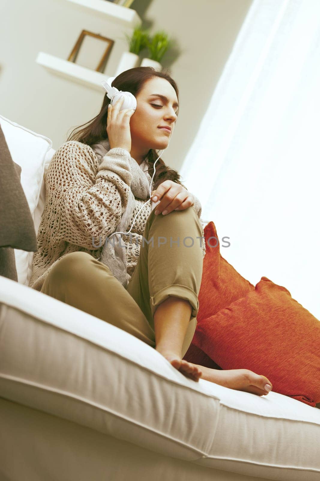 Living room, A young woman is sitting on her sofa, enjoying a moment of peace while listening to music with headphones