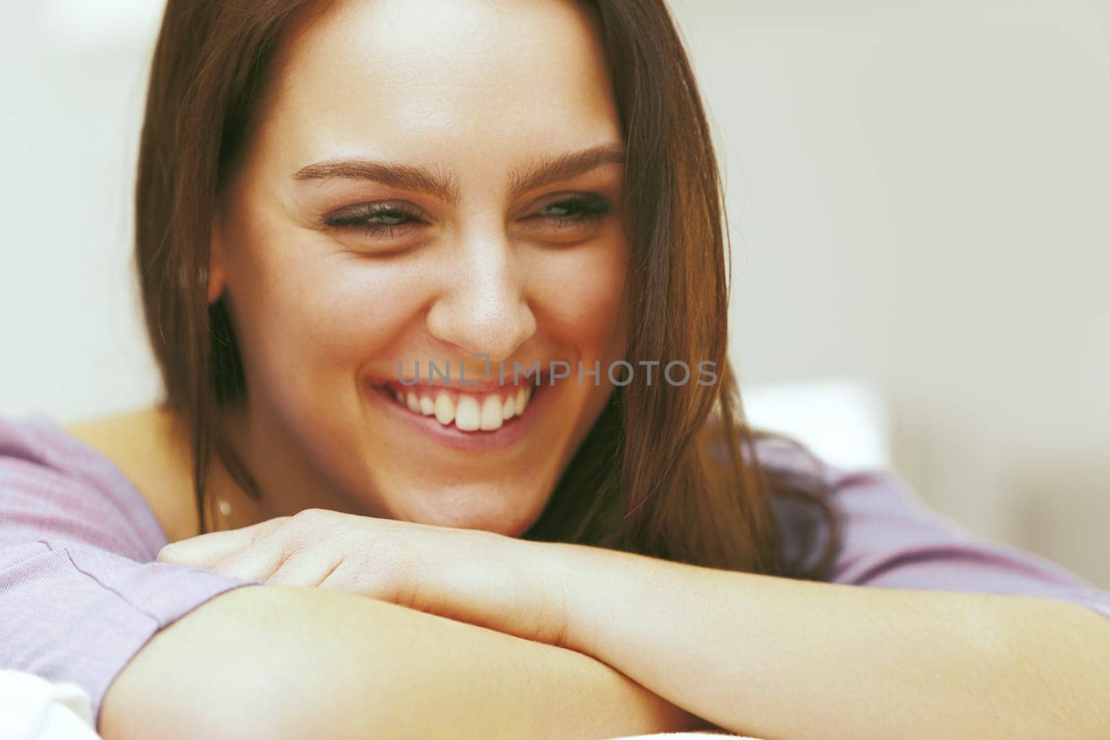 Living room, A beautiful young woman is smiling and relaxing at home with her head on her arms