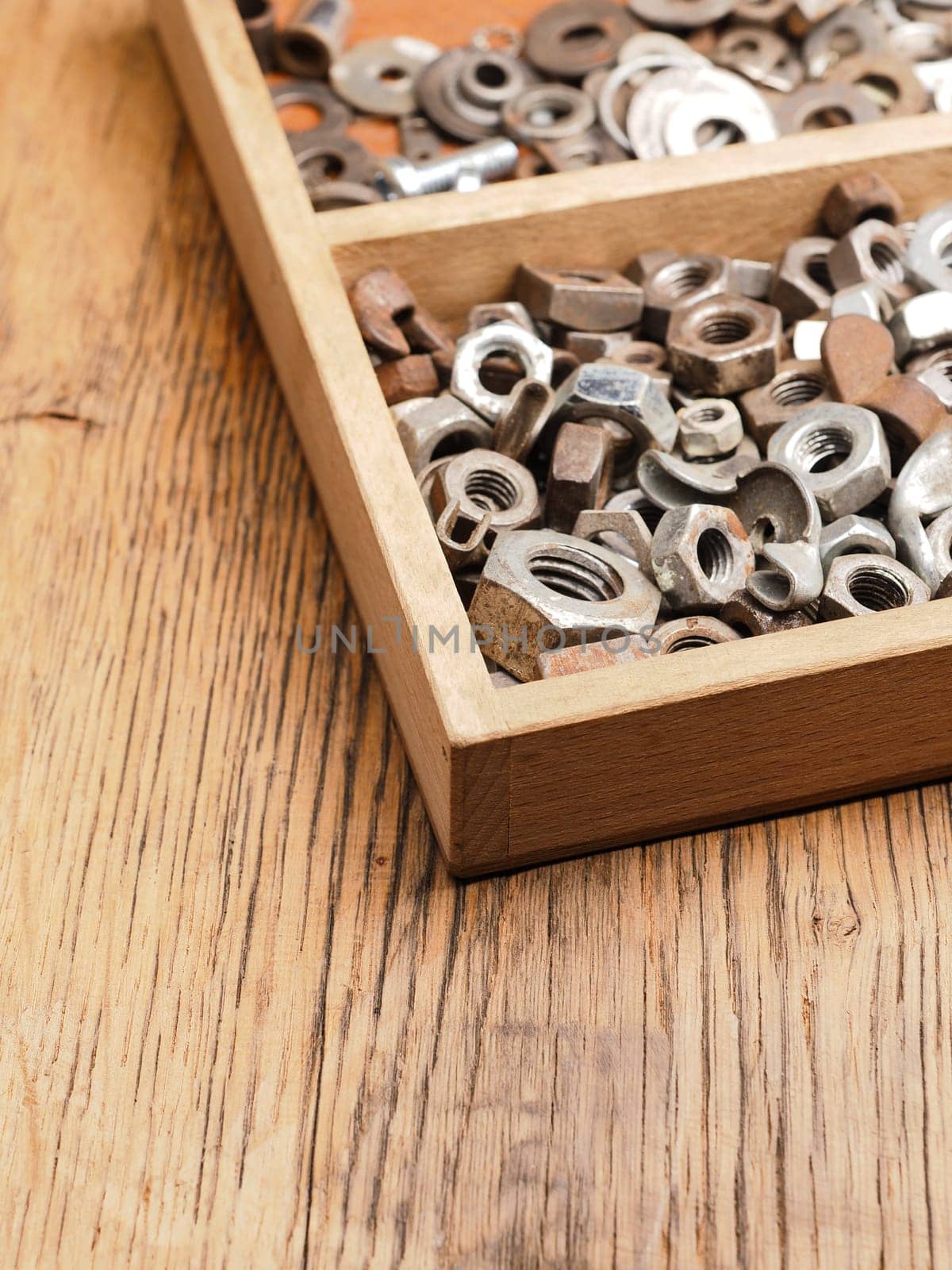 Old rusty bolts and nuts in a wooden box on a workbench
